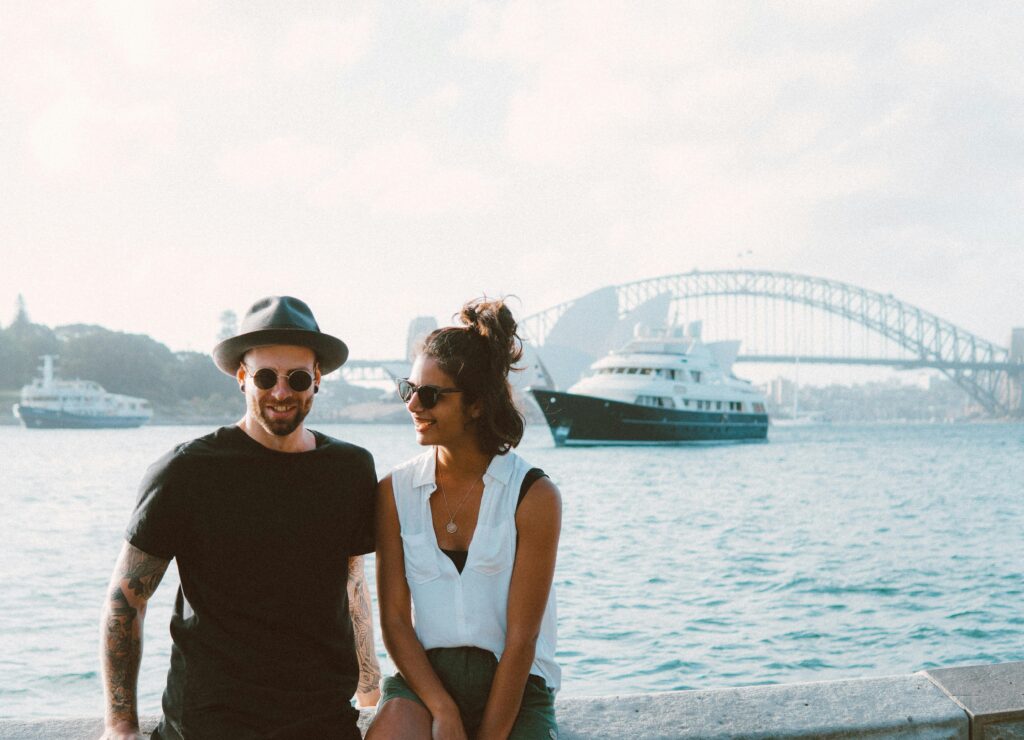 A happy couple enjoying a sunny day by Sydney Harbour with the iconic bridge in the background.